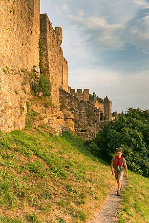 Child hiking outside the walls of the mediavel ancient city of Carcassonne at sunset