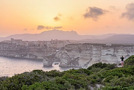 Aa young woman photographs the village of Bonifacio at sunset Aa young woman photographs the village of Bonifacio at sunset