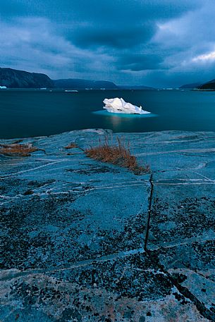 Dark clouds above iceberg in the sea in front  of Ataa a small village of fishermen and seal hunters which was abandoned in the 50s