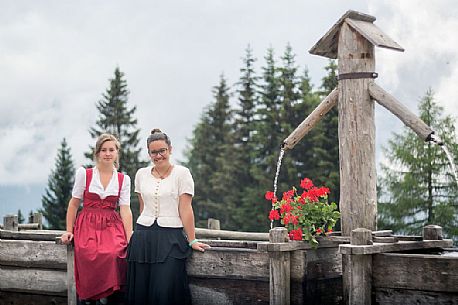 Smiling girls with a traditional dress at Rinfreddo hut, Comelico, dolomites, Italy