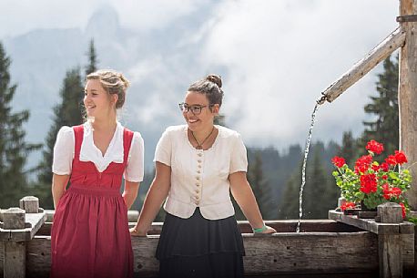 Smiling girls with a traditional dress at Rinfreddo hut, Comelico, dolomites, Italy