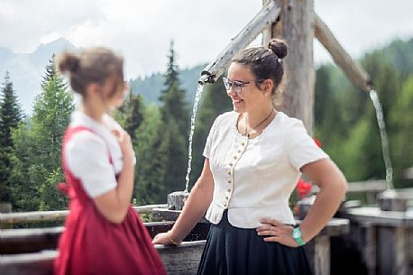 Smiling girls with a traditional dress at Rinfreddo hut, Comelico, dolomites, Italy