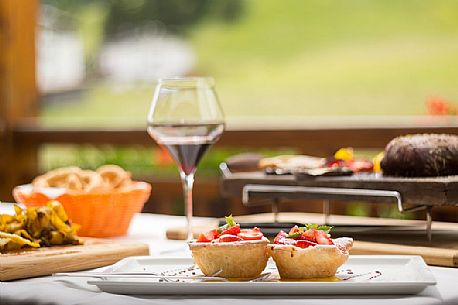 The typical cuisine of the restaurant Skay: dumplins with speck, tagliatelle with venison ragout and little cake with strawberries and custard, Comelico, Italy