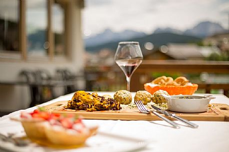 The typical cuisine of the restaurant Skay: dumplins with speck, tagliatelle with venison ragout and little cake with strawberries and custard, Cadore, Italy