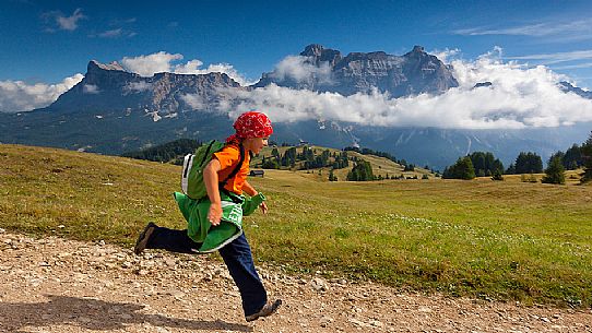Child runs on Pralongi meadows, Badia Valley, South Tyrol, Dolomites, Italy