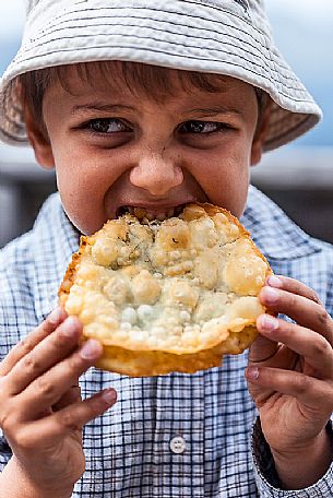 Hungry child eats Turtres, traditional ladin food, South Tyrol, Dolomites, Italy Hungry child eats Turtres, traditional ladin food, South Tyrol, Dolomites, Italy