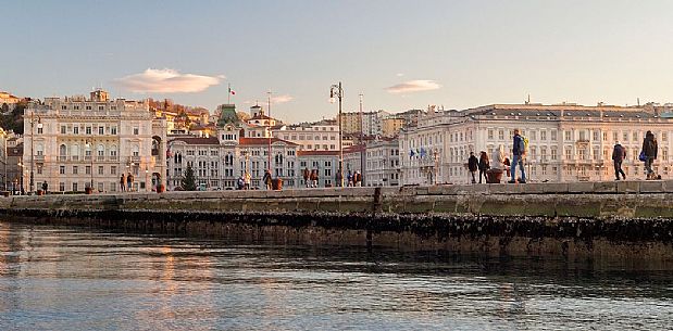 People are walking at Molo Audace, in background Piazza Unit d'Italia, view from the sea of Trieste, Italy
