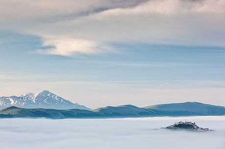 low cloud over rolling hills and the small village of Castelluccio di Norcia, Sibillini National Park, Italy