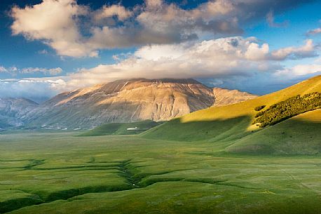 Last lights on Piano Grande Plateau with visible the karst Fosso dei Mergani and in the background Vettore Mount and its fault, Sibillini National Park, Italy Last lights on Piano Grande Plateau with visible the karst Fosso dei Mergani and in the background Vettore Mount and its fault, Sibillini National Park, Italy