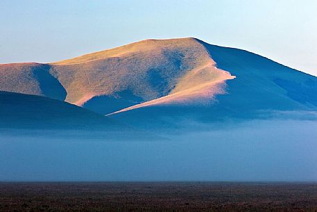 Fog and clouds at dawn on Sibillini meadows, Castelluccio di Norcia, Sibillini National Park, Italy