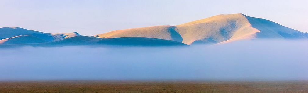 Fog and clouds at dawn on Sibillini meadows, Castelluccio di Norcia, Sibillini National Park, Italy Fog and clouds at dawn on Sibillini meadows, Castelluccio di Norcia, Sibillini National Park, Italy