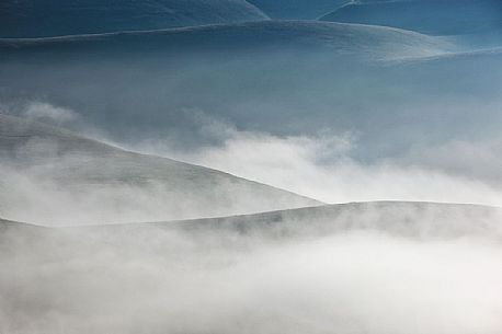 Fog and clouds at dawn on Vettore meadows, Castelluccio di Norcia, Sibillini National Park, Italy