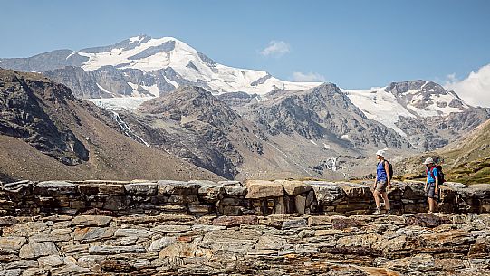 Hikers in high Martello valley and in the background the Cevedale glacier, Stelvio national park, Italy Hikers in high Martello valley and in the background the Cevedale glacier, Stelvio national park, Italy