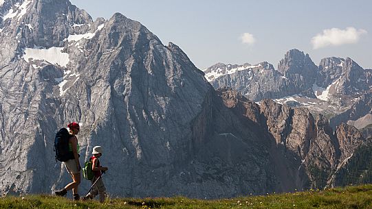 Hikers along the Viel del Pan path, in the background the Marmolada mountain range, dolomites, Italy