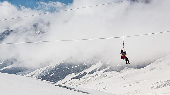Tourist has fun on theAletsch glacier, floating on the steel cable over crevasses, Jungfraujoch, Berner Oberland, Switzerland, Europe Tourist has fun on theAletsch glacier, floating on the steel cable over crevasses, Jungfraujoch, Berner Oberland, Switzerland, Europe