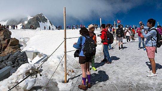 Tourists on the Top of the Jungfraujoch or Top of Europe admiring the Aletsch glacier, the largest in Europe, Bernese alps, Switzerland, Europe Tourists on the Top of the Jungfraujoch or Top of Europe admiring the Aletsch glacier, the largest in Europe, Bernese alps, Switzerland, Europe