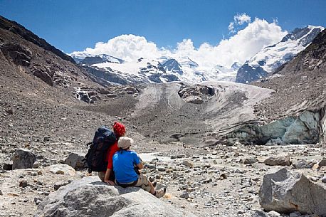 Hikers in Val Morteratsch valley, in the backgrond the glacier and the Bernina mountain range, Pontresina, Engadine, Canton of Grisons, Switzerland, Europe