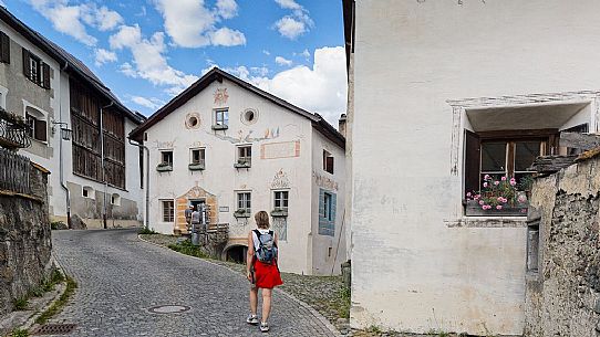 Tourist in the old road of Guarda a tipical village with houses ornated with old painted stone 17th Century buildings, Scuol, Engadine, Canton of Grisons, Switzerland, Europe