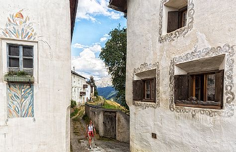 Tourist in the old road of Guarda a tipical village with houses ornated with old painted stone 17th Century buildings, Scuol, Engadine, Canton of Grisons, Switzerland, Europe Tourist in the old road of Guarda a tipical village with houses ornated with old painted stone 17th Century buildings, Scuol, Engadine, Canton of Grisons, Switzerland, Europe