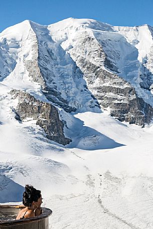 Tourist enjoing in the outdoor jacuzzi pool, in the background the Piz Palu in the Bernina mountain range, Diavolezza Hut, Pontresina, Engadin, Canton of Grisons, Switzerland, Europe
 