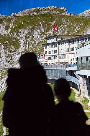 Tourists silhouette looking the Pilatus Klum hotel on Pilatus mountain from summit station of Cogwheel Railway , Lucerne, Border Area between the Cantons of Lucerne, Nidwalden and Obwalden, Switzerland, Europe