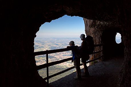 Hikers inside a rocky gallery on the Pilatus mountainn area, in the background the city and the lake of Lucerne, Border Area between the Cantons of Lucerne, Nidwalden and Obwalden, Switzerland, Europe Hikers inside a rocky gallery on the Pilatus mountainn area, in the background the city and the lake of Lucerne, Border Area between the Cantons of Lucerne, Nidwalden and Obwalden, Switzerland, Europe