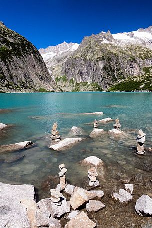 Stacked stones in the shore of Gelmer lake, Gelmersee, a hydroelectric reservoir, Canton of Berne, Switzerland, Europe