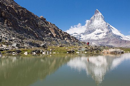 Hiker in the shore of Riffelsee Lake ( Riffel lake ), in the background the Matterhorn or Cervino mount, Zermatt, Valais, Switzerland, Europe