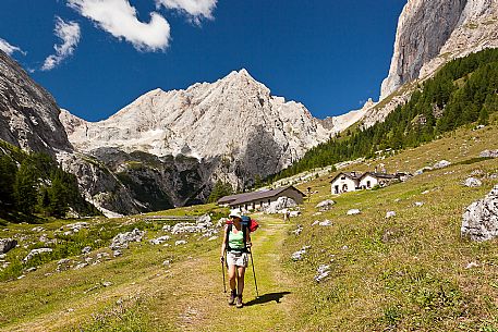 Hiker at the Ombretta hut, in the background the Ombretta peak and the south cliff of Marmolada, Rocca Pietore, dolomites, Veneto, Italy, Europe