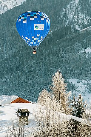 A hot-air balloon flies over the village of Dobbiaco during the balloon festival in Pusteria valley, Dolomites, Trentino Alto Adige, Italy, Europe A hot-air balloon flies over the village of Dobbiaco during the balloon festival in Pusteria valley, Dolomites, Trentino Alto Adige, Italy, Europe