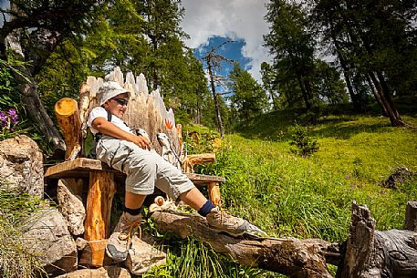 Young hiker rests on a wooden bench, Longiar, San Martino in Badia, Badia valley, dolomites, South Tyrol, Italy, Europe


