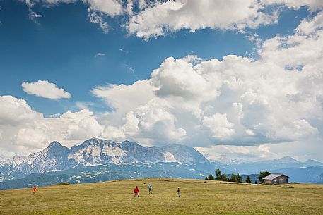 Children play on the high pasture of San Martino in Badia, in the background the Sasso della Croce and the Fanes dolomites,  Badia valley, South Tyrol, Italy, Europe