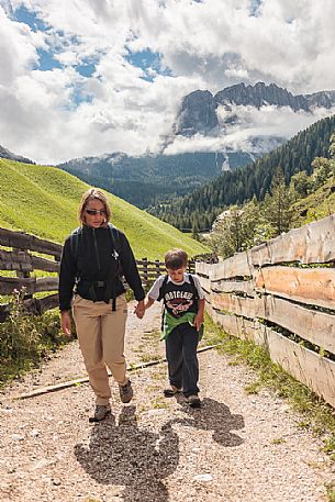 Mother and child walk in valle dei Mulini valley, in the background the dolomites of Puez, Badia valley, Trentino Alto Adige, Italy, Europe