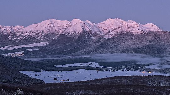 Twilight on the Cansiglio plateau surrounded by the forest, in the background the Monte Cavallo mountain range Veneto, Italy, Europe