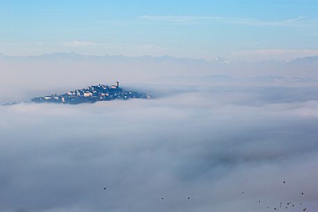 The small village of Conzano Monferrato in the fog, on the background the Alps, Monferrato, Piedmont, Italy, Europe The small village of Conzano Monferrato in the fog, on the background the Alps, Monferrato, Piedmont, Italy, Europe