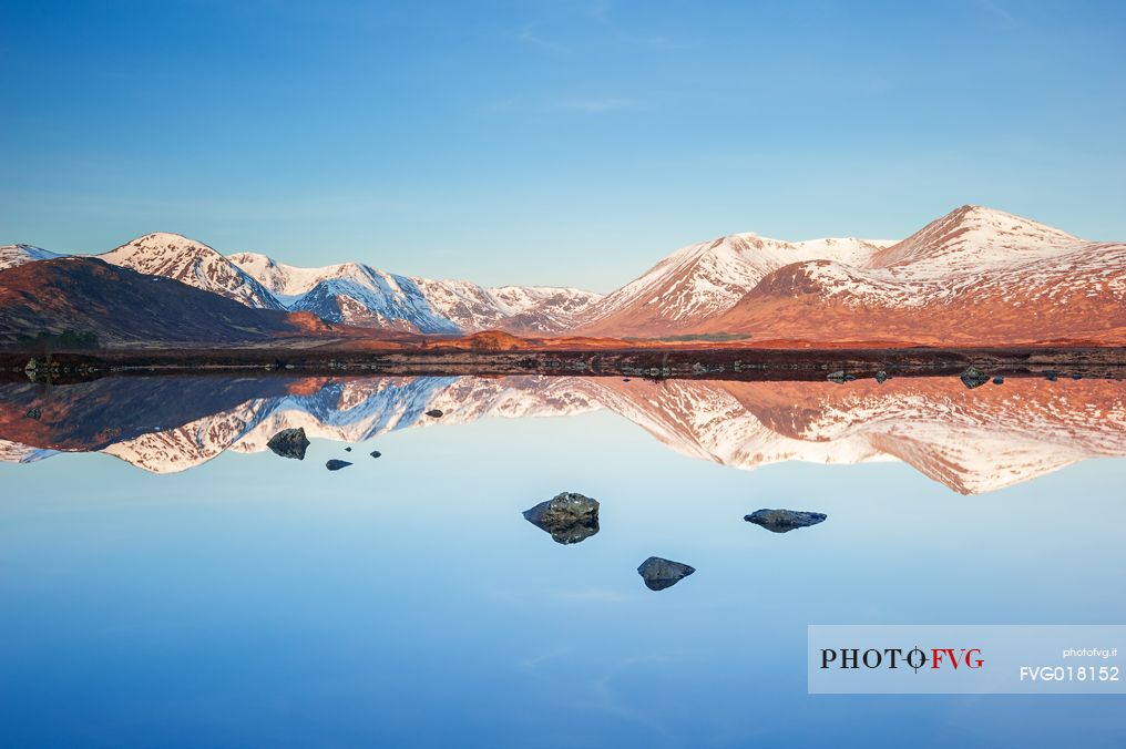 Only the stones emerging from the waters of Loch Nah-Achlaise reveal the presence of the water itself in this perfect reflection at sunrise.