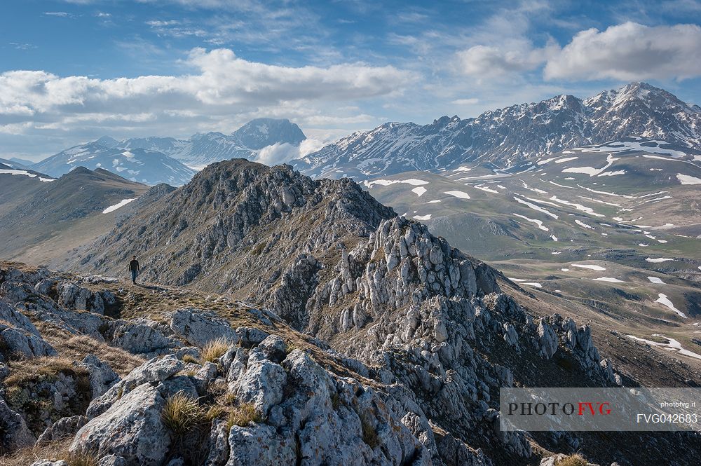a hiker walks on the crest of Mount Bolza in the plateau of Campo Imperatore, Gran Sasso national park, Abruzzo, Italy, Europe