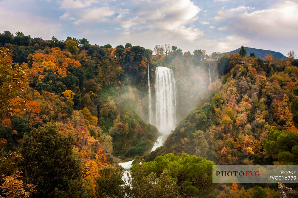 The Marmore waterfall surrounded by woods with autumn colors
