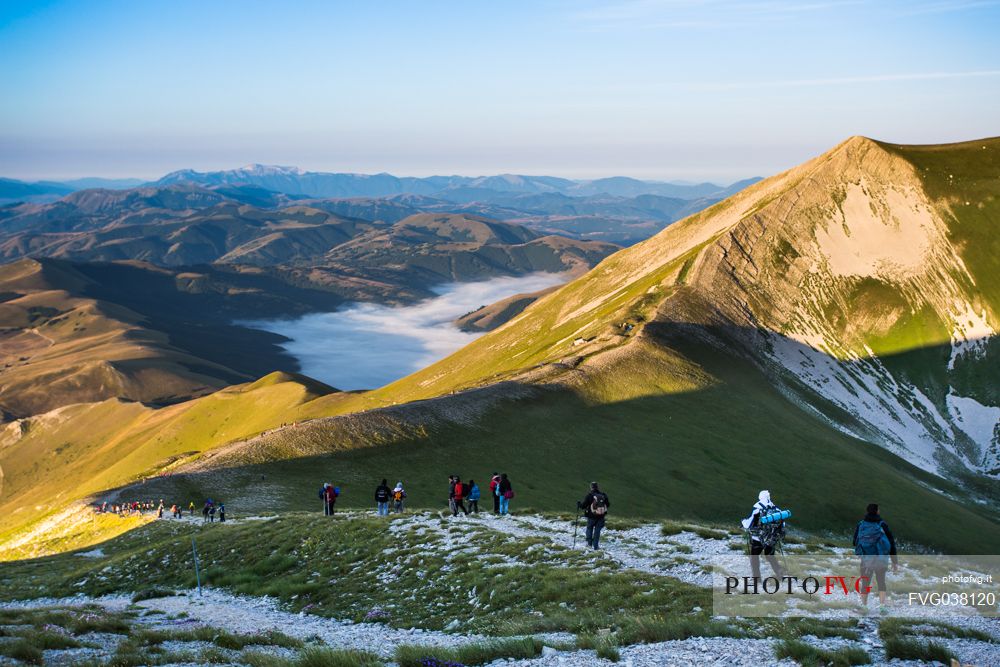 Hikers coming down from Mount Vettore in the Monti Sibillini national park mountains, Castelluccio di Norcia, Umbria, Italy, Europe.