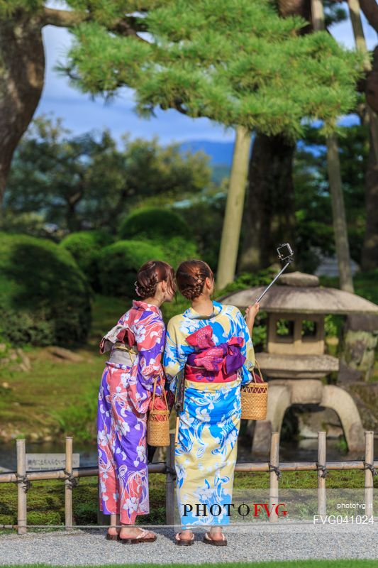 Two girls in kimono take a selfie in the Kenroku-en garden in Kanazawa, Japan