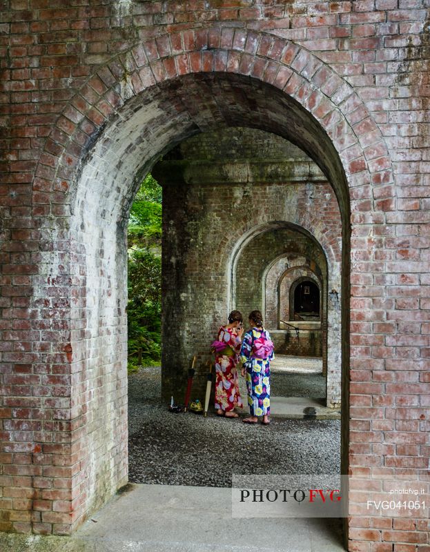 Two Japanese girls in kimono under the arches of the ancient aqueduct of the Nanzen ji temple in Kyoto, Japan