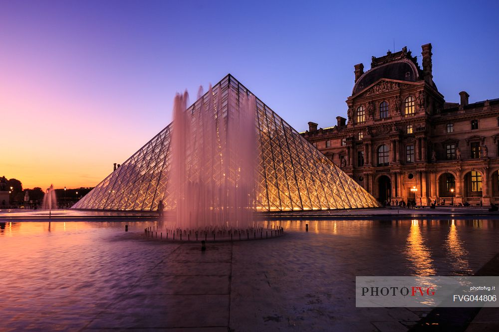 Sunset lights at the Louvre square with the glass pyramid and the fountain, Paris, France, Europe
