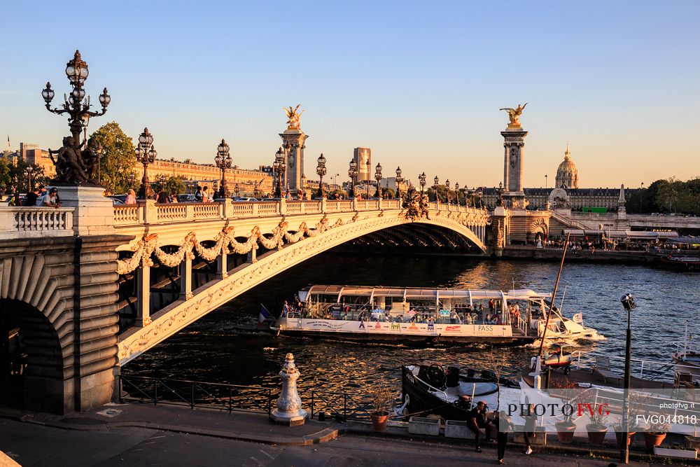 The Alexander III bridge at sunset while passing a Bateau Mouche, Paris, France, Europe