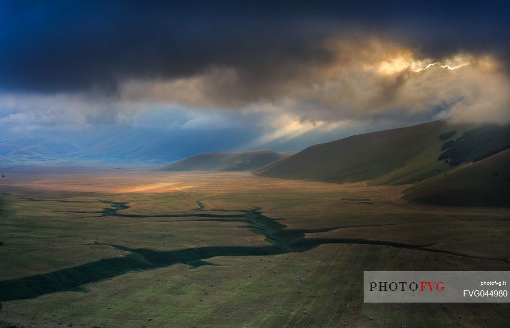 The first rays of sun illuminate the Pian Grande plain of Castelluccio di Norcia at dawn, Umbria, Italy, Europe