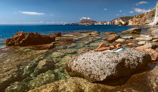 Colored boat in a little cove of Ponza Island. A sea cave in the background.