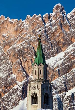 A view of Cortina D'Ampezzo with cathedral's bell tower; in the background mount Pomaganon