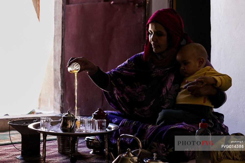 A Saharawi woman preparing tea for guests with her baby