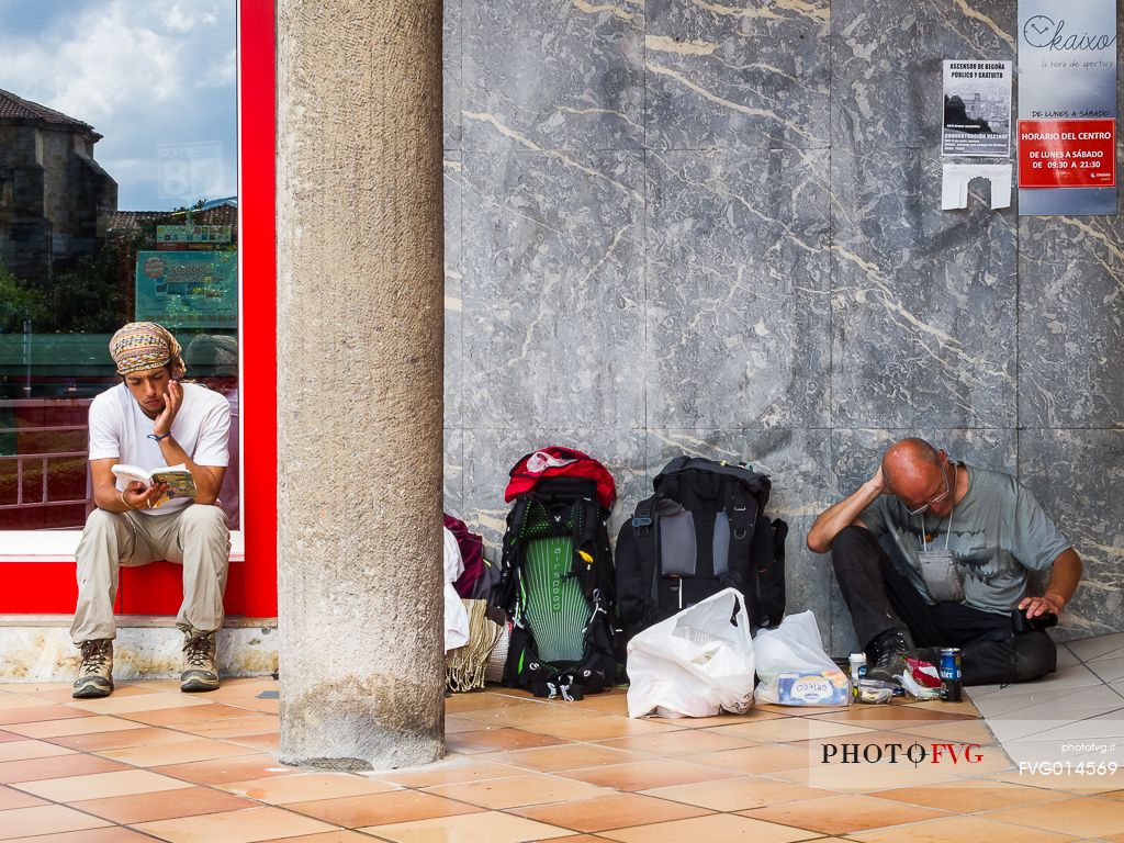 Two pilgrims rest sitting on the floor