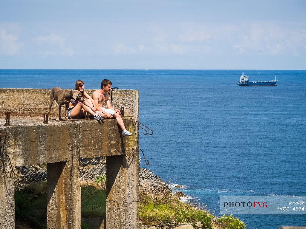 A young girl and a young boy sitting near the ocean with their dog