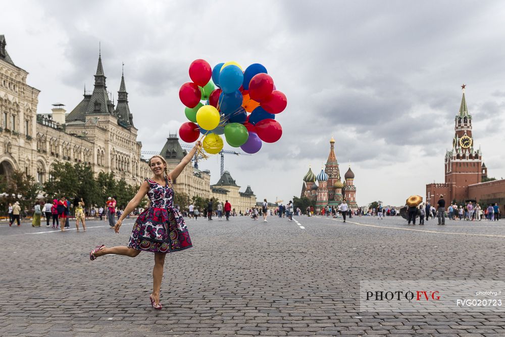 A young girl with some colored balloons posing for a photo in the Red Square in Moscow, Russia